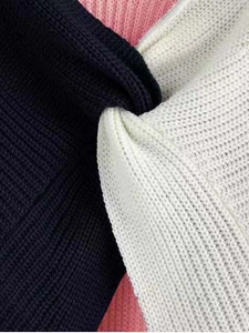 Macro texture showing multi-color black, white, and pink knit fabric detailing on the sweater