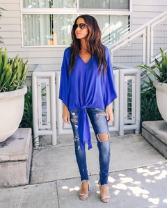 Detail of royal blue chiffon top featuring a V-neckline and adjustable tie-knot waist detail