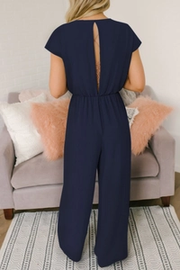 Detail of deep V-neck backless jumpsuit with lace-up tie in elegant navy blue fabric