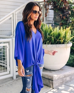 Detail of royal blue chiffon V-neck blouse with butterfly sleeves and stylish hem knot tied