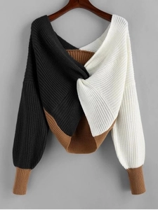 Detail of color-block knit sweater featuring front twist knot and ribbed lantern sleeves