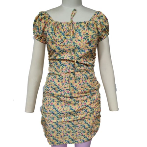 Detail of yellow floral mini dress featuring ruched bodycon design and drawstring neckline