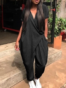 Détail d'une combinaison noire ample à manches courtes avec décolleté en V et lien à la taille