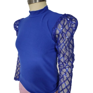 Dettaglio del top blu reale con maniche in mesh trasparente e motivi di paillettes