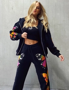 Detail of black tracksuit set featuring colorful butterfly digital print on sleeves and pants