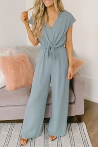 Detail of the high-waisted tie-waist knot on a light blue V-neck wide-leg jumpsuit