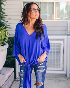 Detail of royal blue chiffon blouse featuring V-neckline and stylish front knot design