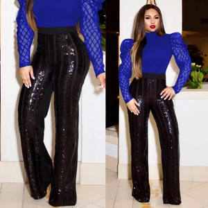 Dettaglio top blu con maniche in rete e pantaloni neri con strisce di paillettes