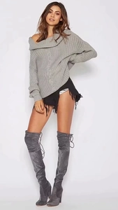 Detail of grey off-shoulder cable knit sweater paired with stylish over-knee suede boots