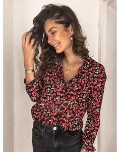 Détail du motif floral rose rouge sur chemise à manches longues avec bijoux dorés