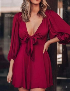 Détail d'une robe mini rouge foncé avec décolleté plongeant en V et nœud frontal