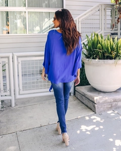 Back view of a loose cobalt blue V-neck chiffon top with ruffled sleeves and side tie details