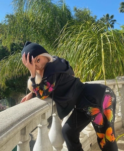 Detail of colorful butterfly prints on black hooded sweatshirt and joggers set