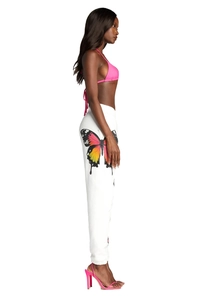 Detail view of colorful butterfly print on white joggers and pink halter bikini top