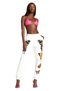 Detail of vibrant butterfly print on white jogger pants with pink bikini top styling