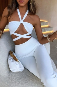 Detail of white halter neck crop top set with sleek high waist trousers on model
