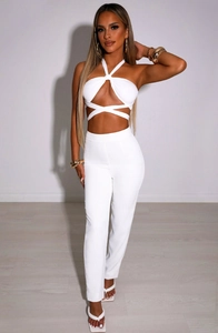 Detail of white cross halter top with midriff wrap ties and high waist straight trousers