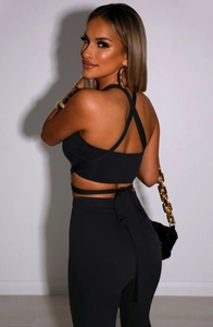 Detail view of black cross-back bandage crop top and high-waisted slim fit trousers