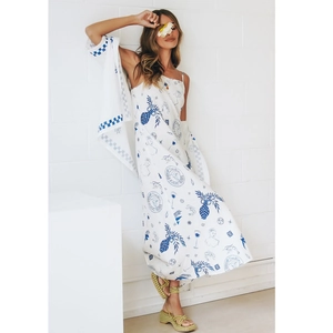 Detail of white summer dress featuring blue artistic hand-painted prints and vacation motifs