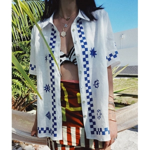 Detail of white short sleeve shirt featuring blue hand-painted geometric prints and patterns