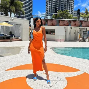 Close-up of bright orange ribbed knit maxi dress with a side slit by the pool