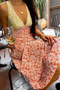Detail of color-block floral maxi dress showing yellow and orange print waist seam