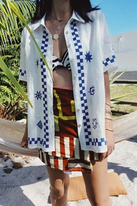 Detail of short sleeve shirt with hand-painted patterns and checkered trim in a resort setting
