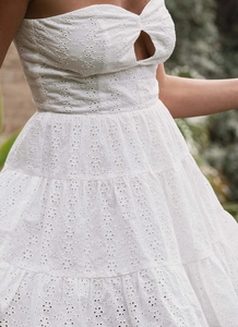 Detailed close-up of white eyelet lace embroidery and tiered skirt of the dress