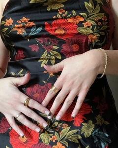 Detail of vintage floral dress paired with gold rings and twisted rope chain bracelet