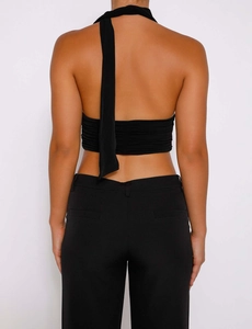 Détail du crop top noir avec licou, design dos nu et texture plissée subtile et moderne