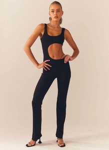 Detail of minimalist black jumpsuit featuring side cutout and sleek sleeveless design
