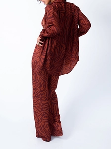 Détail de l'ensemble chemise ample et pantalon large à imprimé zébré marron-rouge