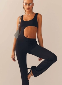 Detail of minimalist black jumpsuit featuring an asymmetric waist cutout and slim fit design