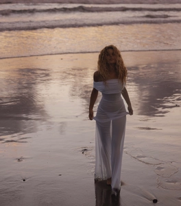 Close-up of elegant off-shoulder white mesh maxi dress on sunset beach during golden hour