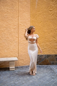 Détail macro d'une robe longue en satin champagne avec lacets et découpes à la taille