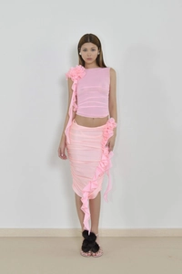 Détail d'un ensemble en maille rose avec fleur 3D et volants latéraux élégants