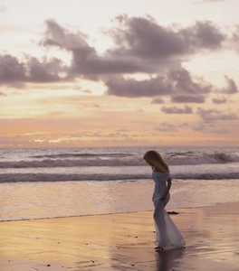 Detail of white off-shoulder slim maxi dress in breathable mesh fabric at the beach