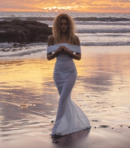 Close-up of white off-shoulder mesh dress with sheer fabric details on a sunset beach