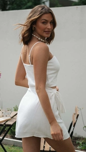 Detail of white two-piece summer set with smocked back top and side-tie mini skirt