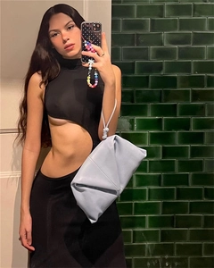 Détail d'un sac à main en cuir noué bleu clair associé à une robe longue ajourée