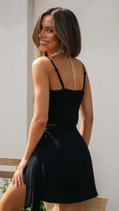 Detail of black smocked crop top and mini skirt set with side tie design for summer