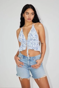 Close-up of blue floral halter top with ruffled hem and raw edge denim shorts detail