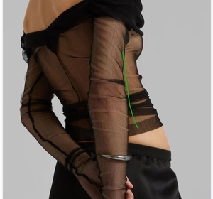Detailed view of black sheer mesh off-shoulder long sleeve top with ruched texture