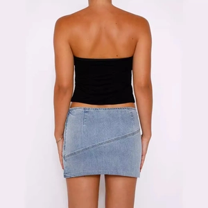 Back view of a light blue denim mini skirt with diagonal seams and a low-rise fit