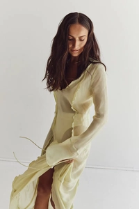 Detail of light yellow sheer chiffon dress with vertical ruffles and long sleeves