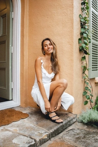 Detail of white V-neck strap dress with ruffle trim and stylish black block heel sandals