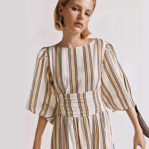 Détail des manches bouffantes rayées et de la taille plissée sur une robe d'été