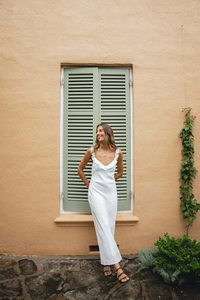 Detail view of the elegant V-neckline and ruffled shoulder straps on a white summer dress