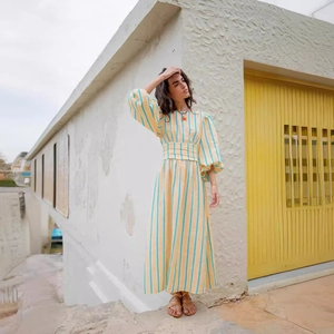 Détail d'une robe longue plissée à rayures jaunes et manches bouffantes à la lumière d'été