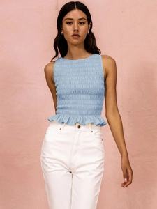 Detail of light blue sleeveless top featuring smocked texture and peplum hem design